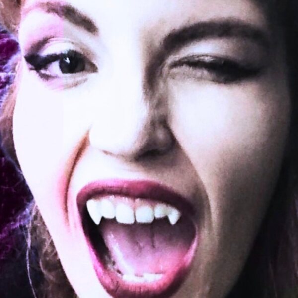 Lady Lovely Lich winking, fangs out, lit in magenta